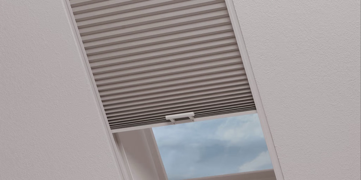 Motorized honeycomb skylight shade partially open on an angled ceiling skylight