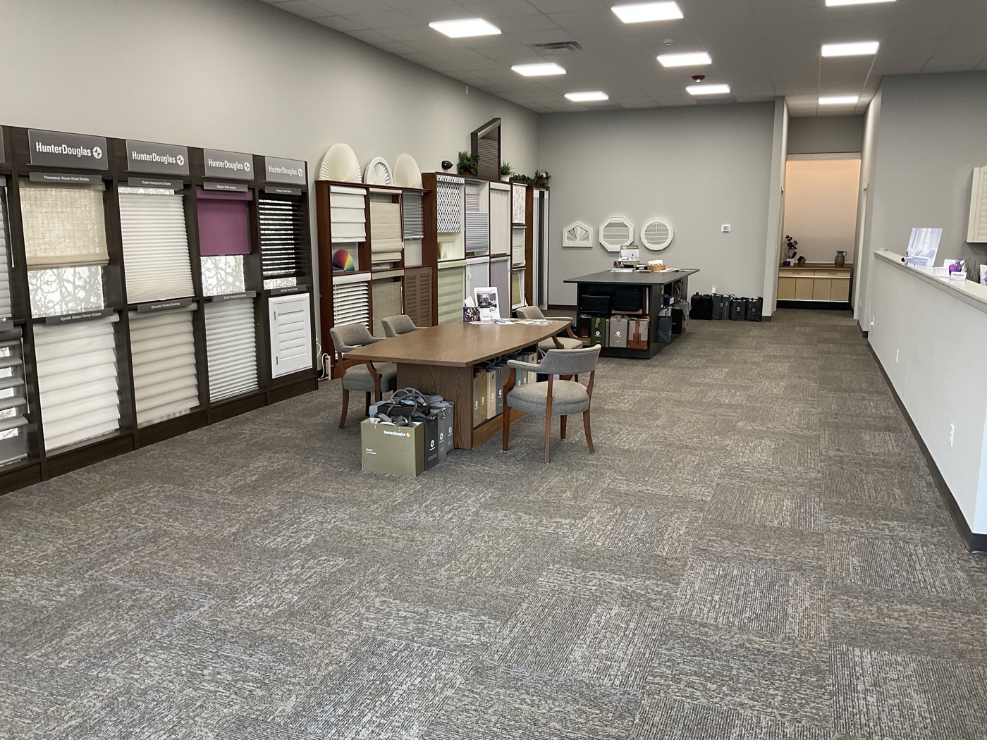 Wall of full-size Hunter Douglas shade displays beside a design table in the Accent on Windows showroom