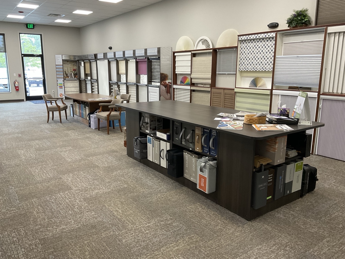 Sample island stocked with shade and drapery fabric books beside a wall of shade and shutter displays in the Accent on Windows showroom