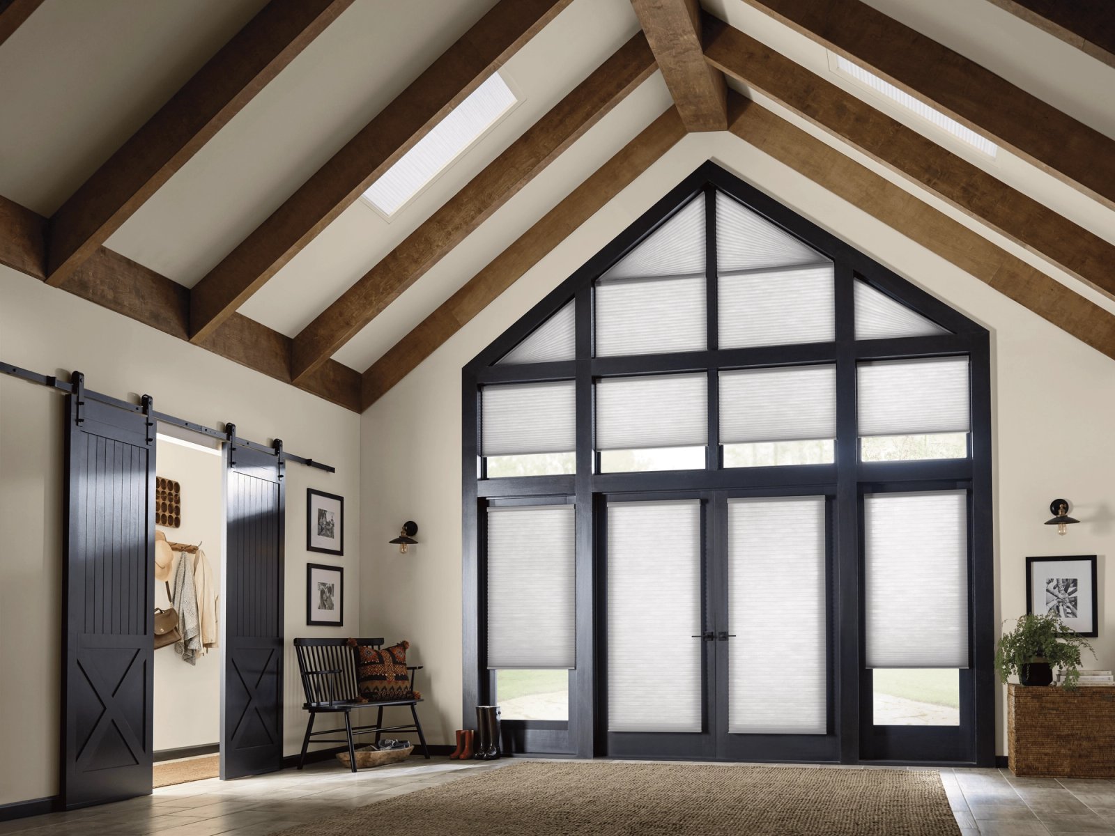 Gabled two-story window wall fitted with honeycomb shades, under a beamed vaulted ceiling with a skylight
