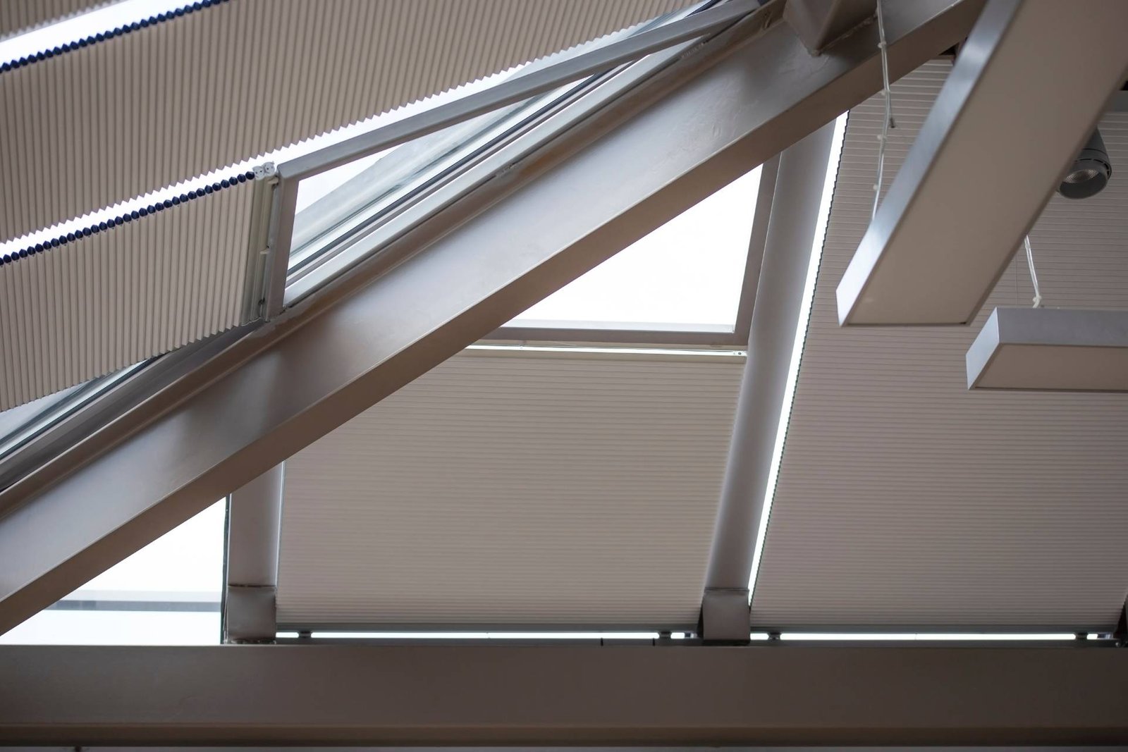 Cellular skylight shades running on side tracks across a sloped ceiling