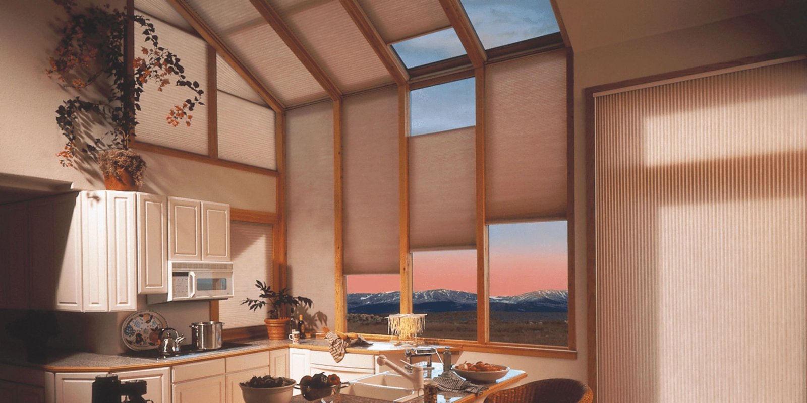 Vaulted wood ceiling in a kitchen with honeycomb shades covering the skylights